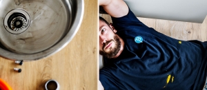 Plumber lying under a kitchen sink inspecting drain connections and pipework in Brisbane