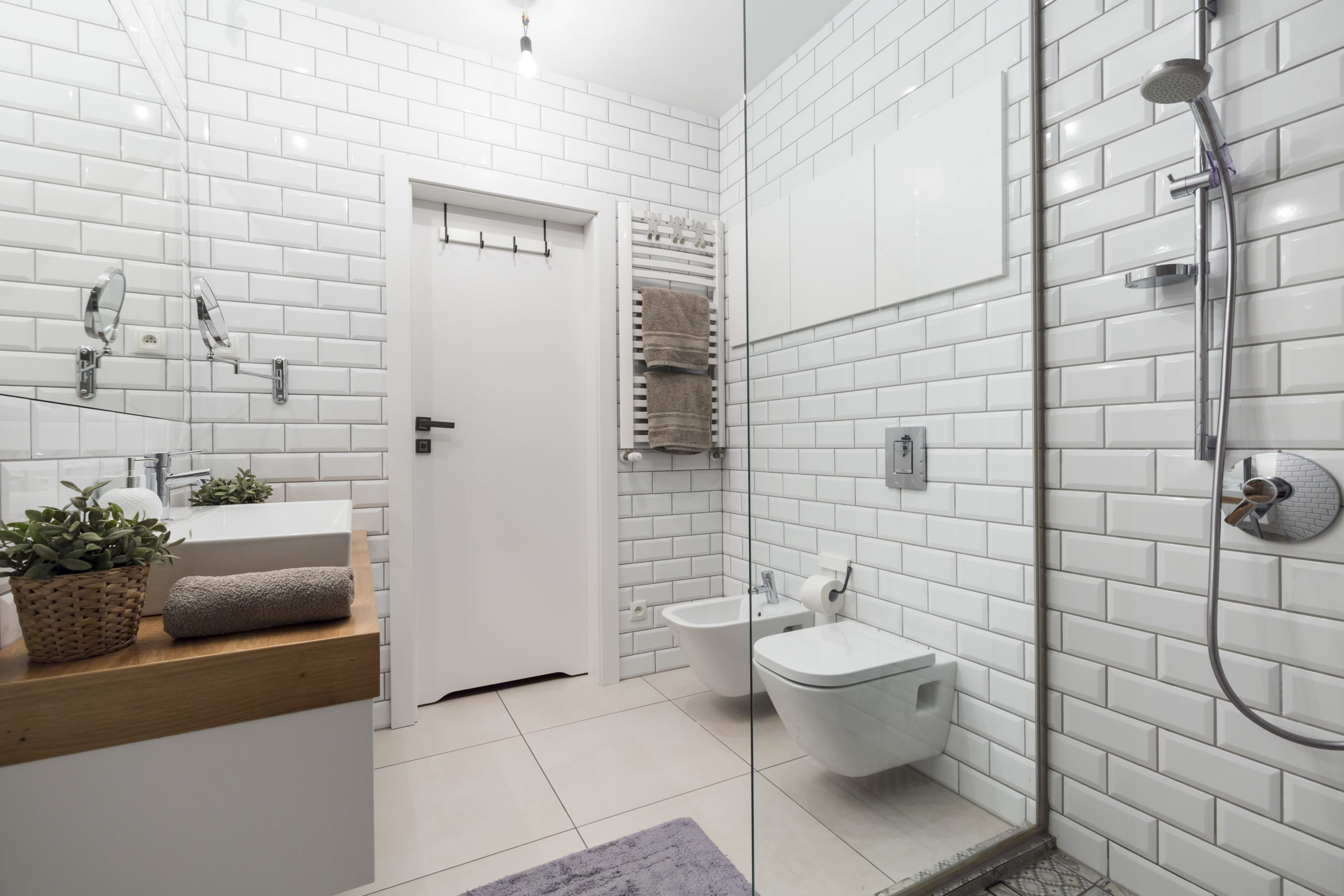 Modern bathroom with walk-in shower, wall-mounted toilet, white subway tiles and vanity sink