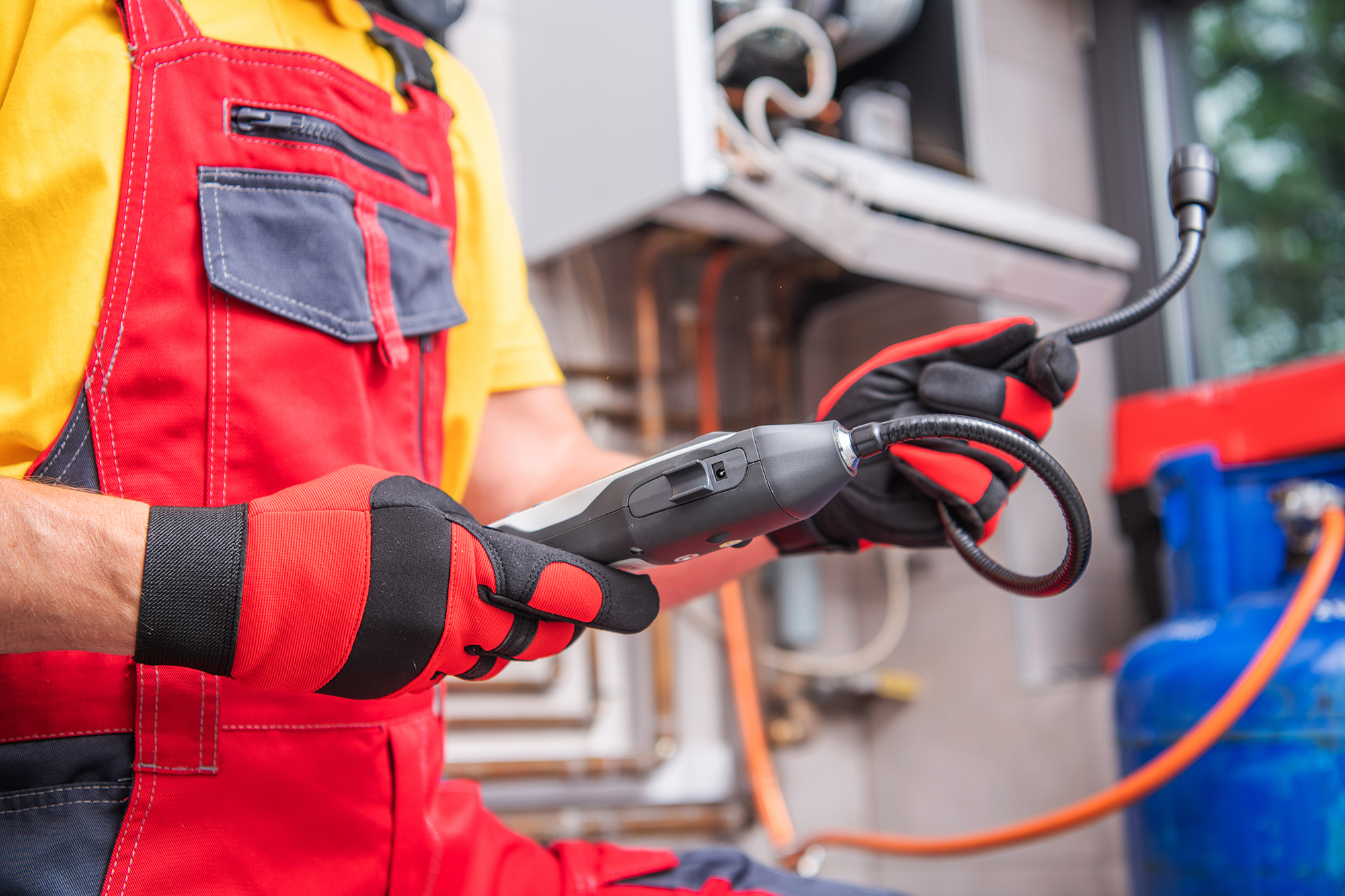 Plumber using a gas leak detector device to inspect a residential gas system