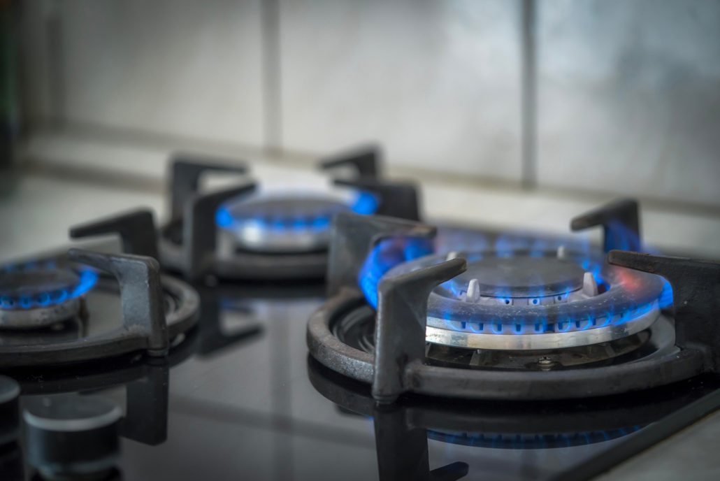 Gas stove burners lit with blue flames on a modern kitchen cooktop