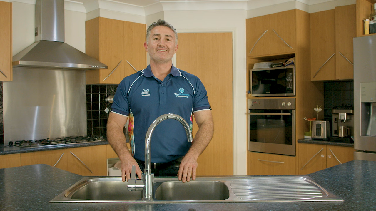 Joseph, Director of The Brisbane Plumbers, beside a kitchen sink after a tap and plumbing installation in Brisbane