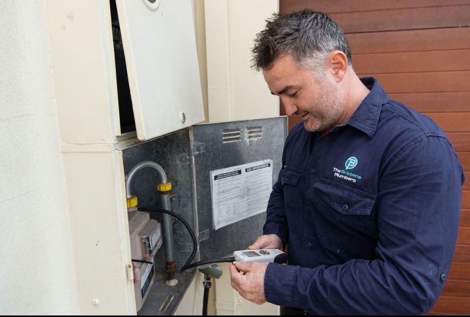 Brisbane plumber performing a gas safety test on an outdoor gas meter using a digital testing device