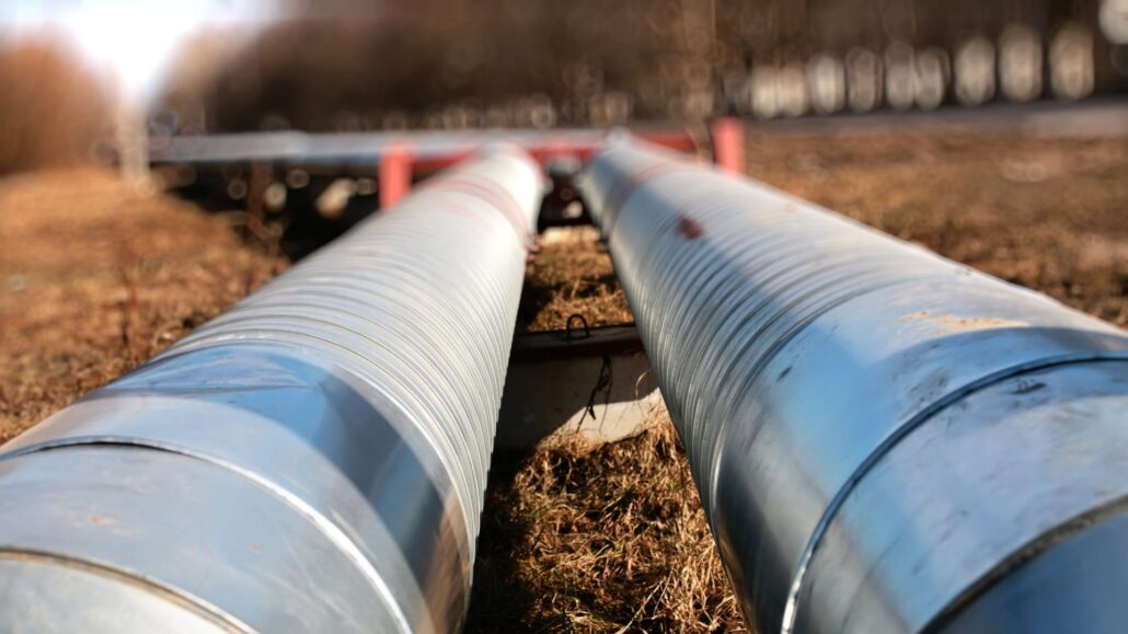 Close-up of two large metallic pipes lying on the ground in an industrial setting