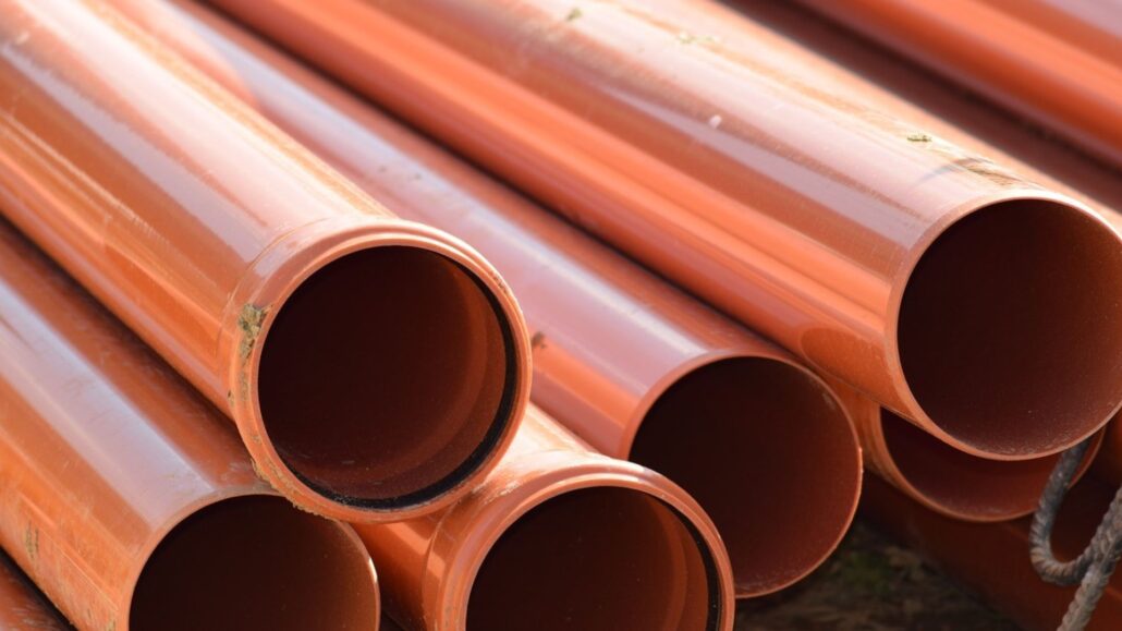 Close-up of stacked orange PVC pipes.