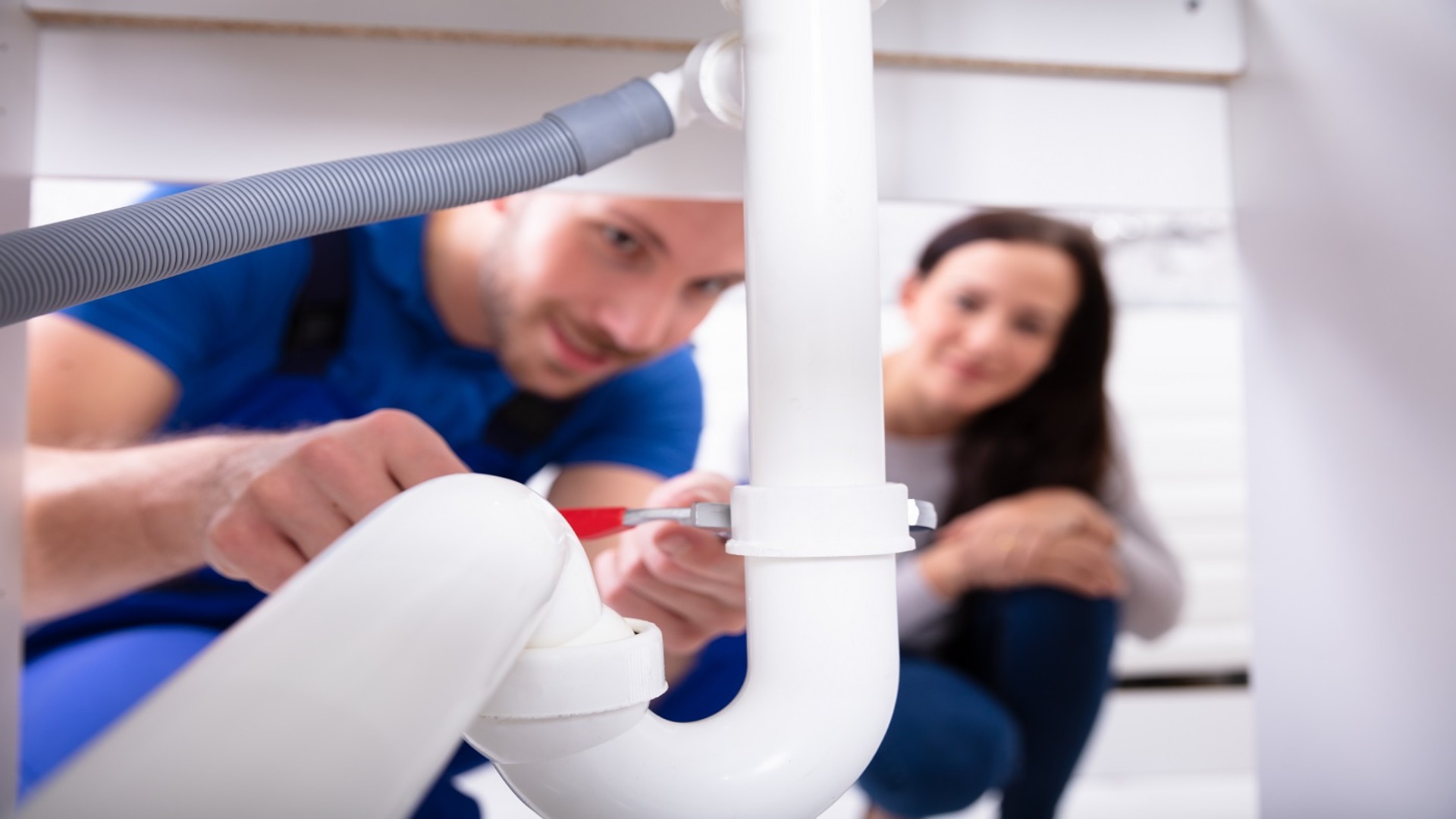 Licensed plumber repairing under-sink pipes for a Brisbane homeowner