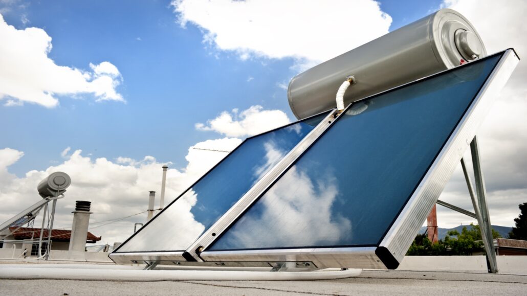 Solar water heater system installed on a roof, featuring solar panels and a storage tank, harnessing sunlight for water heating.