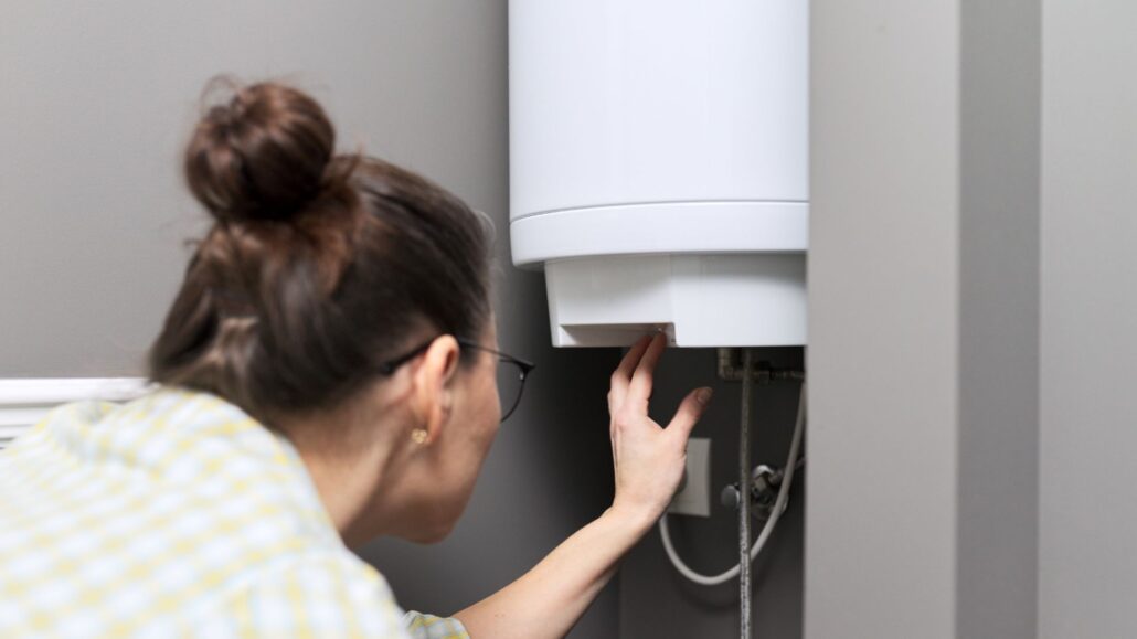 Person inspecting or adjusting a water heater, focusing on the controls, in a modern home setting.