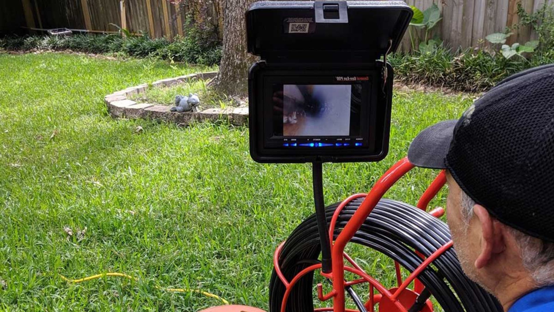 Plumber monitoring a CCTV drain inspection camera screen in a Brisbane backyard