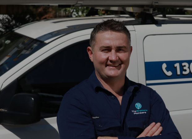 Joseph, Director of The Brisbane Plumbers, standing confidently in front of the service van displaying 1300 576 388