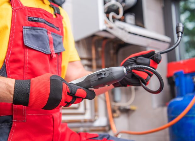 Plumber using a gas leak detector device to inspect a residential gas system