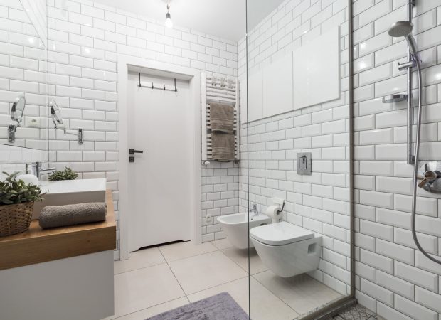 Modern bathroom with walk-in shower, wall-mounted toilet, white subway tiles and vanity sink